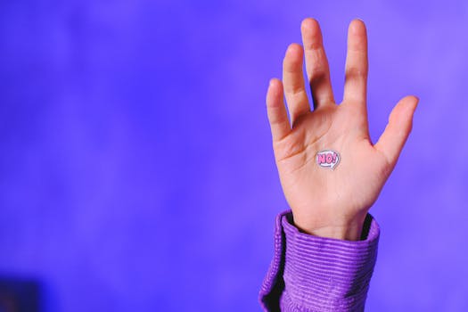 A hand raised with a 'No' sticker, set against a vivid purple background for concept imagery.