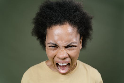 Close-up of an African American woman with afro hair expressing anger in a studio setting.