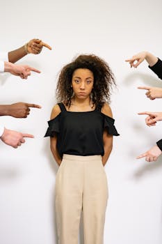 Portrait of a woman surrounded by pointing fingers, conveying themes of accusation and stress.
